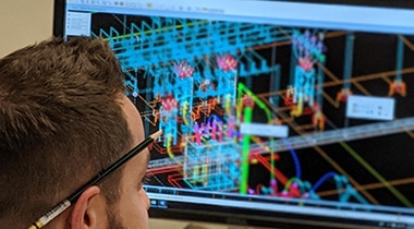 Man looking at computer screen with pencil behind ear